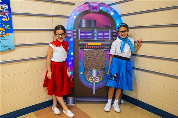two girls in poodle skirts in front of a jukebox